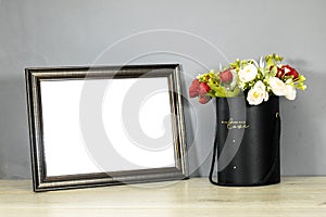 Empty wooden ornate picture frame photo with bouquet of flowers on wood table photo