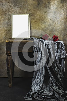 Empty wooden ornate picture frame photo with red roses flowers on wooden table with textile