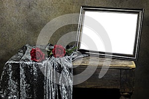 Empty wooden ornate picture frame photo with red roses flowers on wooden table with textile