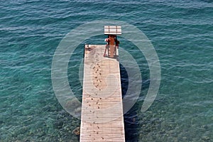 Empty wooden pier in azure sea, aerial view