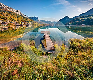 Empty wooden pier in a fishing village. Bright sunny day on Grundlsee lake. Marvelous autumn view of Eastern Alps, Liezen District