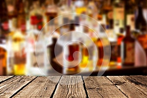 Empty wooden planks against various alcohol bottles in a bar or restaurant. Bar advertisement mockup image