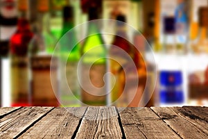 Empty wooden planks against various alcohol bottles in a bar or restaurant. Bar advertisement mockup image