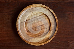 An empty wooden plate with a beautiful texture on a dark wooden table