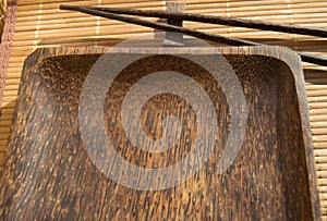 Empty wooden plate and sushi chopsticks on bamboo napkin