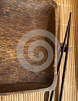 Empty wooden plate and sushi chopsticks on bamboo napkin