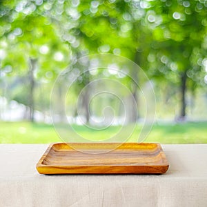 Empty wooden plate on table over blur park nature outdoor in spring and summer with bokeh background, for food display montage