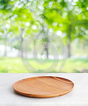 Empty wooden plate on white table over blur green trees nature with bokeh background, Blank wood dish for food display montage