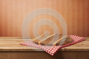 Empty wooden round board on tablecloth over red wall background for product montage