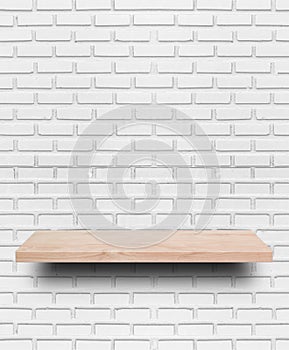 Empty wooden shelf on white brick wall