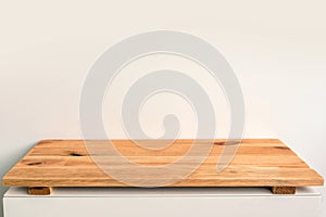 Empty wooden shelf on a white wall, backdrop ready to use for display or montage of products