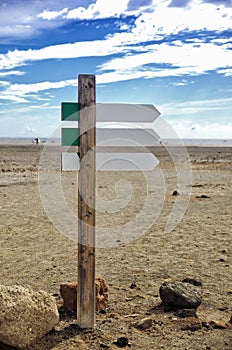 Empty wooden signboard arrow on blurred ocean beach background. Road sign template.