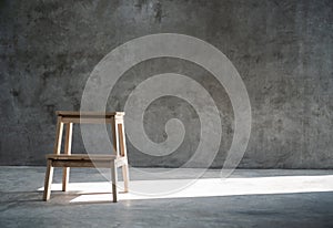 Empty wooden stepladder chair over concrete wall background