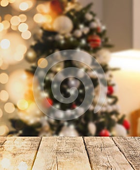 Empty wooden surface and blurred view of Christmas tree in room, space for text. Interior design