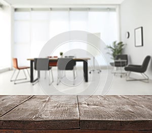 Empty wooden surface and blurred view of office interior, closeup. Space for text