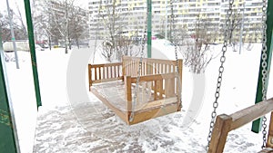 Empty wooden swing bench in winter time with snow