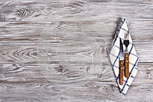 Empty wooden table background and fork and knife on napkin. Dinner, lunch or breackfast concept.