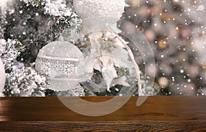 Empty wooden table on the background of snowy decorated Christmas tree branch with white balls. Christmas background. Ready for