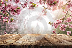 Empty wooden table with blooming spring garden background. Display with spring nature, cherry branches. Free space for product