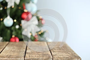 Empty wooden table and blurred fir tree with Christmas lights on background. Space for design