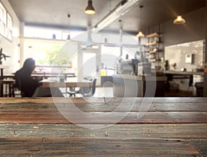 Empty wooden table or counter top with blurred cafe on background