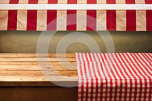 Empty wooden table covered with red checked tablecloth. Background for product montage