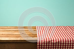 Empty wooden table covered with red checked tablecloth. Background for product montage