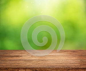 Empty wooden table with defocused sunny abstract green nature background