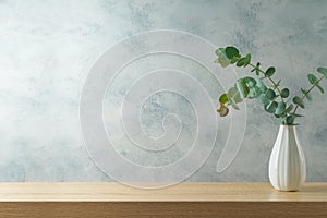 Empty wooden table with eucalyptus plant branches in vase. Interior mock up background for product display