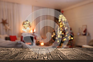 Empty wooden table in festively decorated room with Christmas tree near fireplace. Space for design