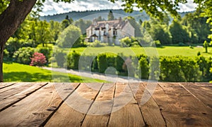 An empty wooden table in the foreground, with a blurred country house in the background against a verdant garden setting