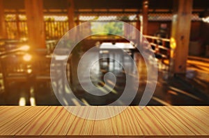 Empty wooden table in front of abstract blurred coffee shop background. For product display montage.