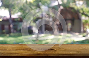 Empty wooden table in front of abstract blurred green of garden and house background. For montage product display or design key