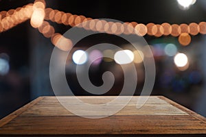 Empty wooden table in front of abstract blurred night light in cafe, restaurant