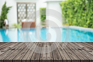 Empty wooden table in front with blurred background of swimming pool