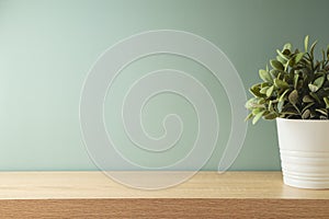 Empty wooden table with home plant decor over green wall background.  Modern interior mock up for design and product display