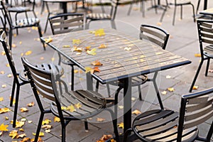 Empty wooden table in the outdoor autumn cafe with metallic black chairs