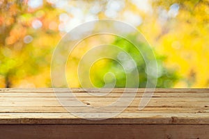 Empty wooden table over autumn nature bokeh