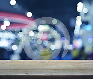 Empty wooden table over defocused light and shadow of shopping m