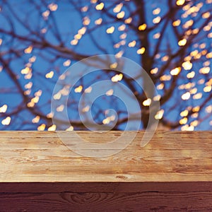 Empty wooden table over night lights decoration and tree background