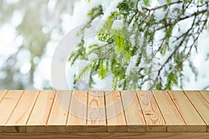 Empty wooden table  over snow pine tree branches background