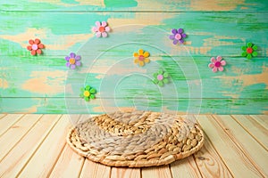 Empty wooden table with round wicker placemat over colorful background