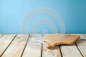 Empty wooden table with tablecloth and cutting board over blue wall  background.  Kitchen mock up for design and product display