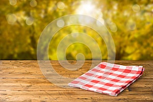 Empty wooden table with tablecloth over autumn nature park background