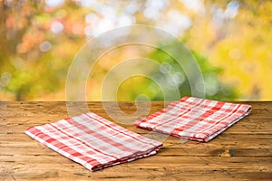 Empty wooden table with tablecloth over autumn nature park background