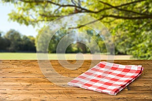 Empty wooden table with tablecloth over autumn nature park background