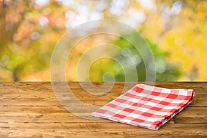 Empty wooden table with tablecloth over autumn nature park background