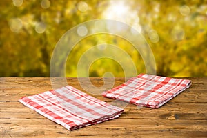 Empty wooden table with tablecloth over autumn nature park background