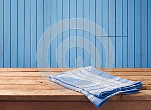 Empty wooden table with tablecloth over blue wood wall background. Background for food product display montage.