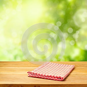 Empty wooden table with tablecloth over garden bokeh background